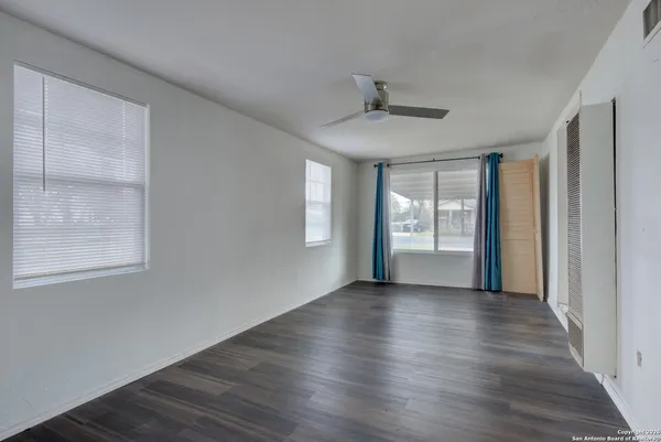 a view of an empty room with wooden floor and a window