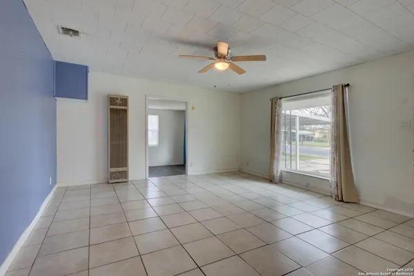 a view of an empty room with window and chandelier fan