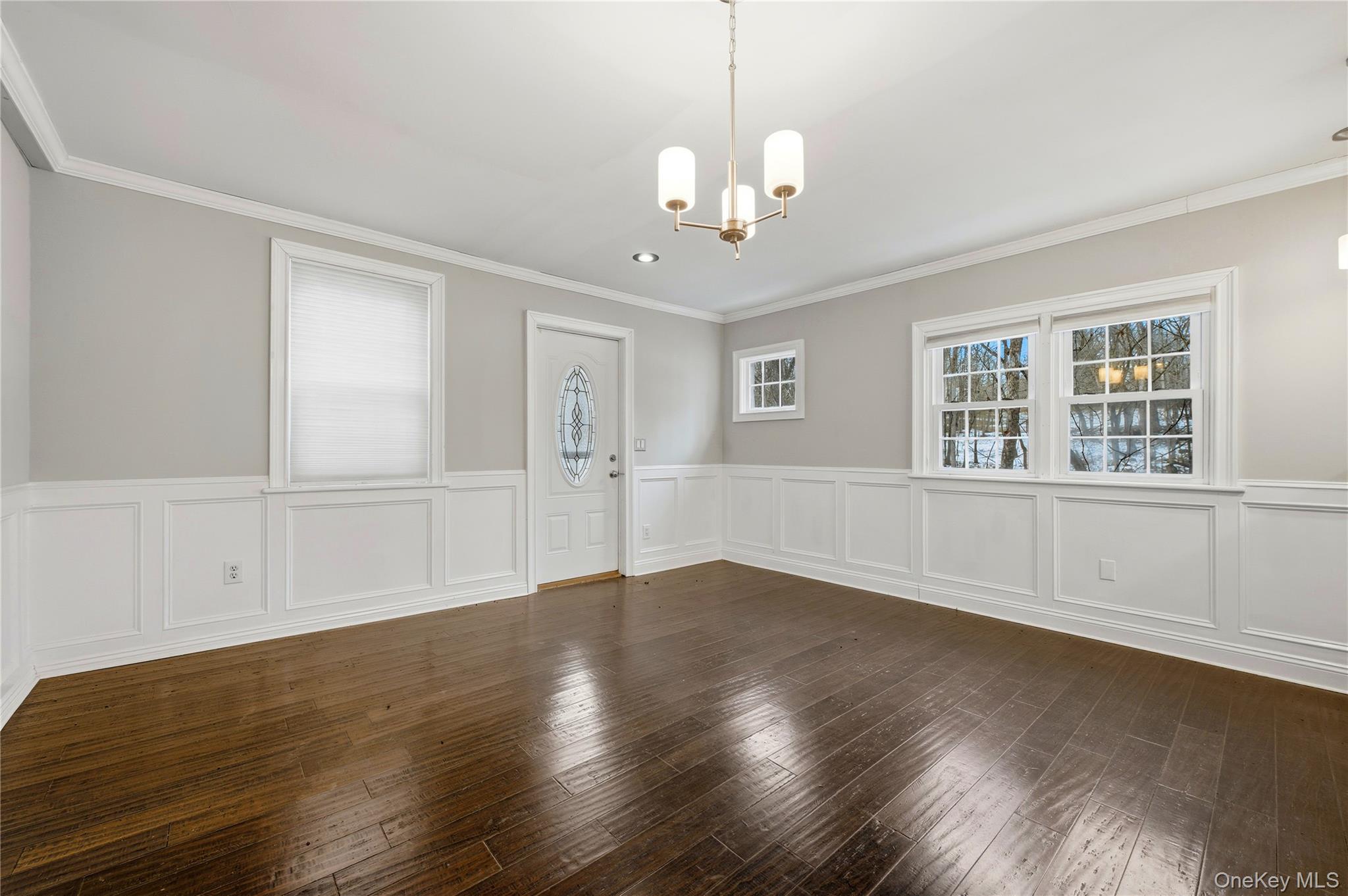293 Highway 94 Warwick, NY 10990 - Photo 7 of 20 Unfurnished dining area featuring plenty of natural light, a chandelier, dark wood-type flooring, ornamental molding, and a wainscoted wall