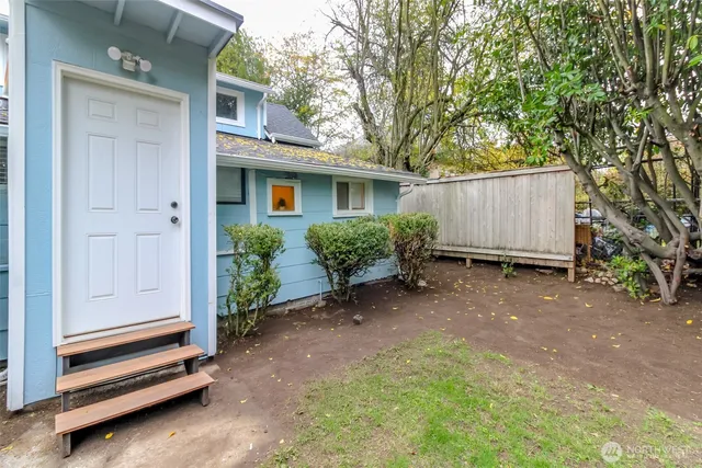 a view of a house with a yard plants and large tree