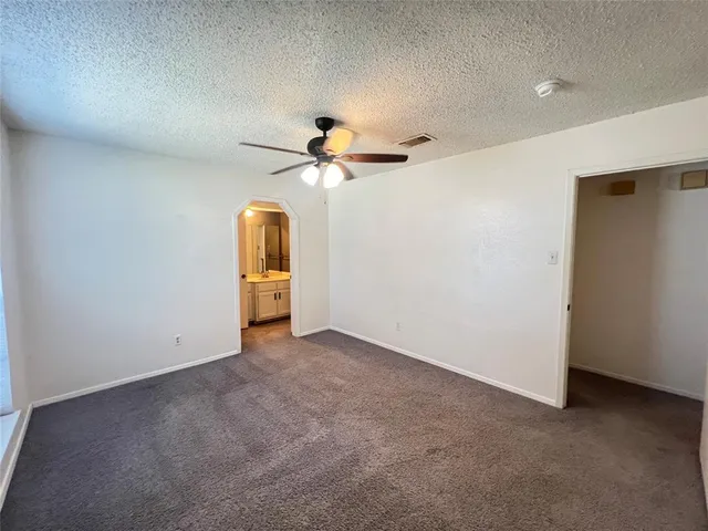 an empty room with chandelier fan and windows