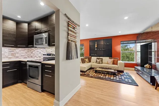 a living room with stainless steel appliances kitchen island granite countertop a stove and a sink