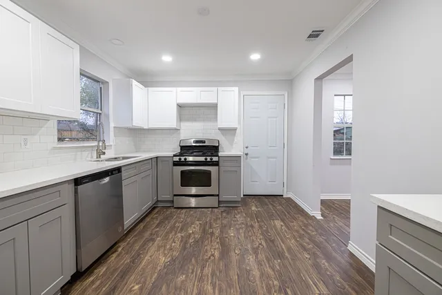 a kitchen with granite countertop a sink cabinets and stainless steel appliances