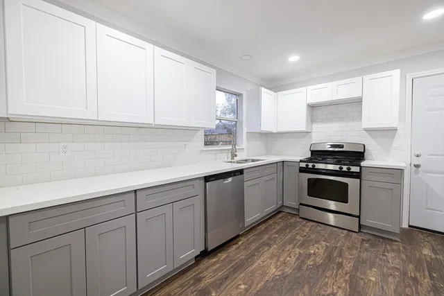 a kitchen with granite countertop a sink cabinets and stainless steel appliances