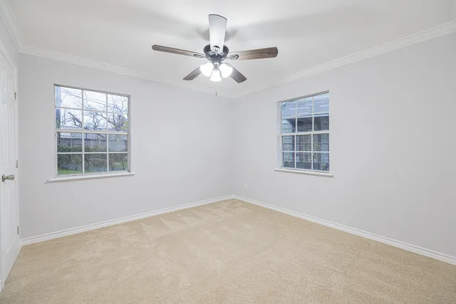 an empty room with windows and fan