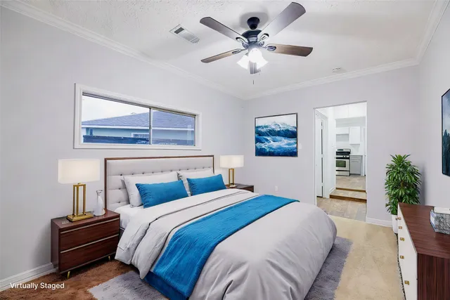 a spacious bedroom with a bed a chandelier and a potted plant on the dresser
