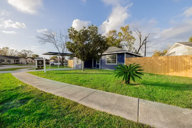 a view of a house with a big yard and palm trees