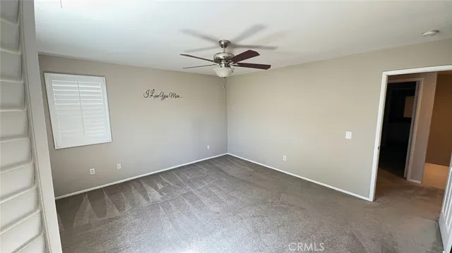 an empty room with a ceiling fan and carpet