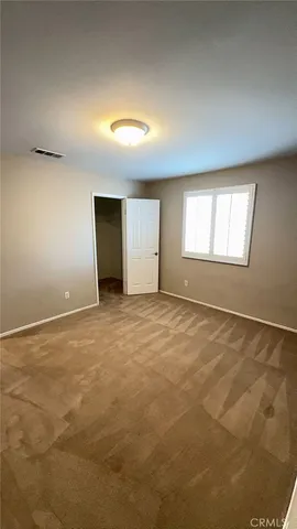 a view of an empty room with closet and wooden door