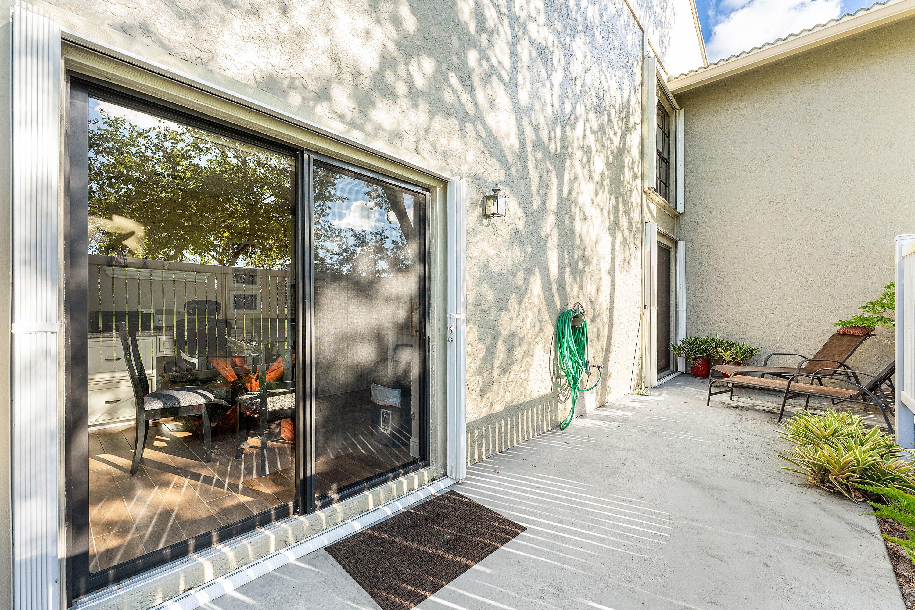 67 Eastgate Drive, Unit C Boynton Beach, FL 33436 - Photo 38 of 62 a view of a porch with chairs and floor to ceiling window
