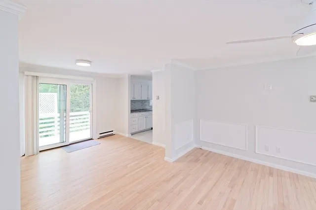 a view of an empty room with a window and wooden floor