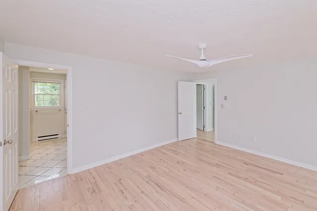 a view of empty room with wooden floor and fan