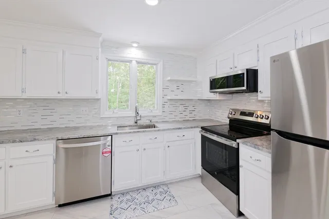 a kitchen with white cabinets sink and stainless steel appliances