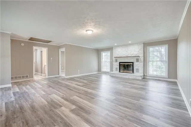 an empty room with wooden floor fireplace and windows