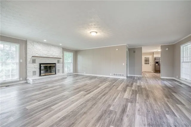 a view of an empty room with wooden floor fireplace and a window