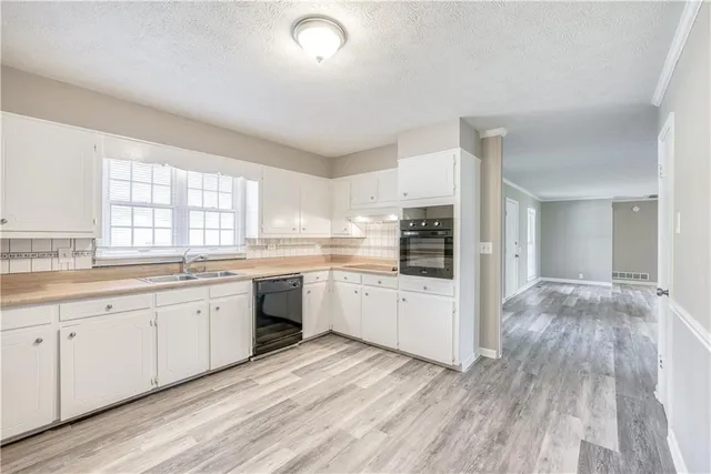 a large kitchen with cabinets wooden floor and stainless steel appliances