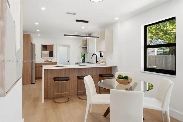 a view of a white house in front of a big yard with large trees