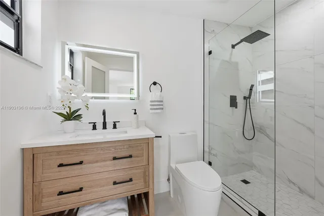 a bathroom with a shower sink vanity mirror and toilet