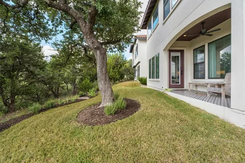 a view of a house with a small yard plants and large tree
