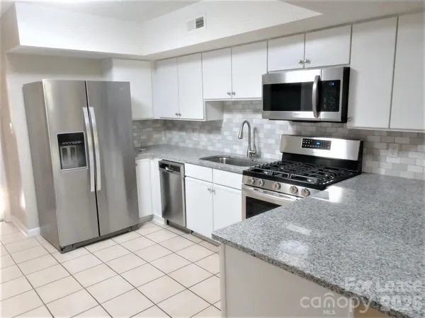 a kitchen with stainless steel appliances granite countertop a stove a sink and a microwave