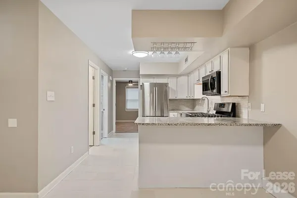 a large kitchen with stainless steel appliances granite countertop a refrigerator a stove a sink dishwasher and white cabinets with wooden floor