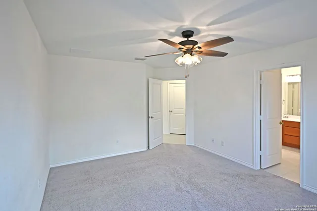 a view of an empty room and window with a ceiling fan