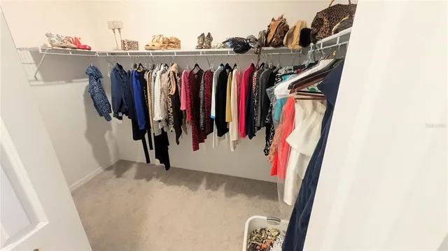 a view of walk in closet with clothes and shoes