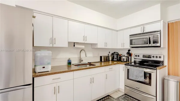a kitchen with stainless steel appliances granite countertop white cabinets sink and stove
