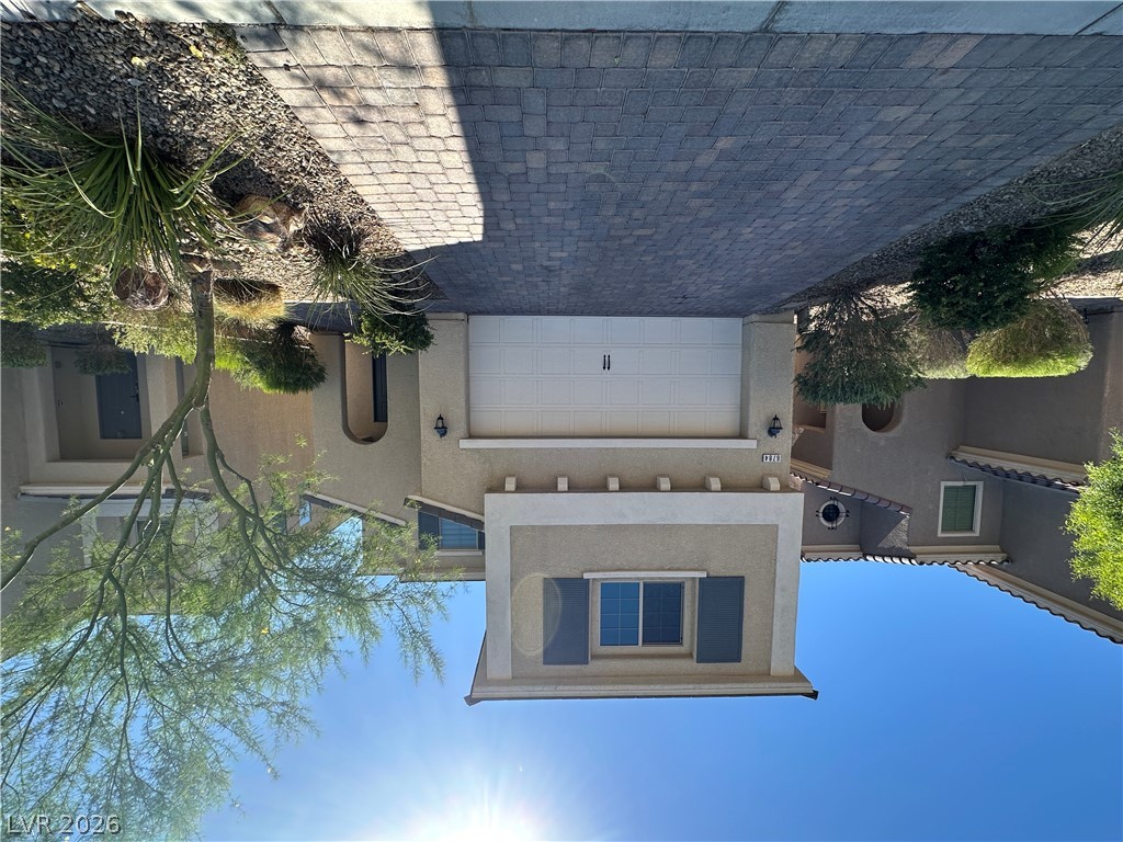 A welcoming façade with an attached garage and a neatly paved driveway, framed by low-maintenance desert landscaping.