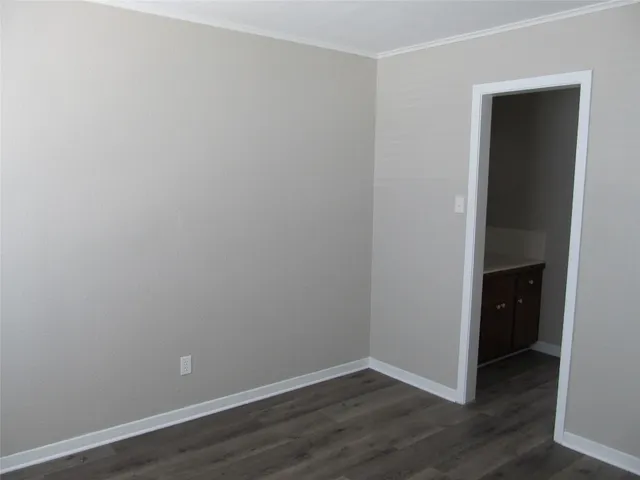 a view of an empty room with wooden floor and closet