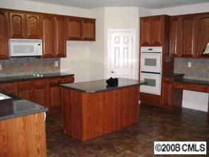 2423 Blueberry Ridge Road Matthews, NC 28105 - Photo 4 of 8 a kitchen with granite countertop wooden cabinets and stainless steel appliances
