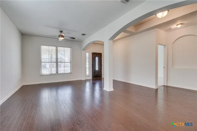 an empty room with wooden floor and windows