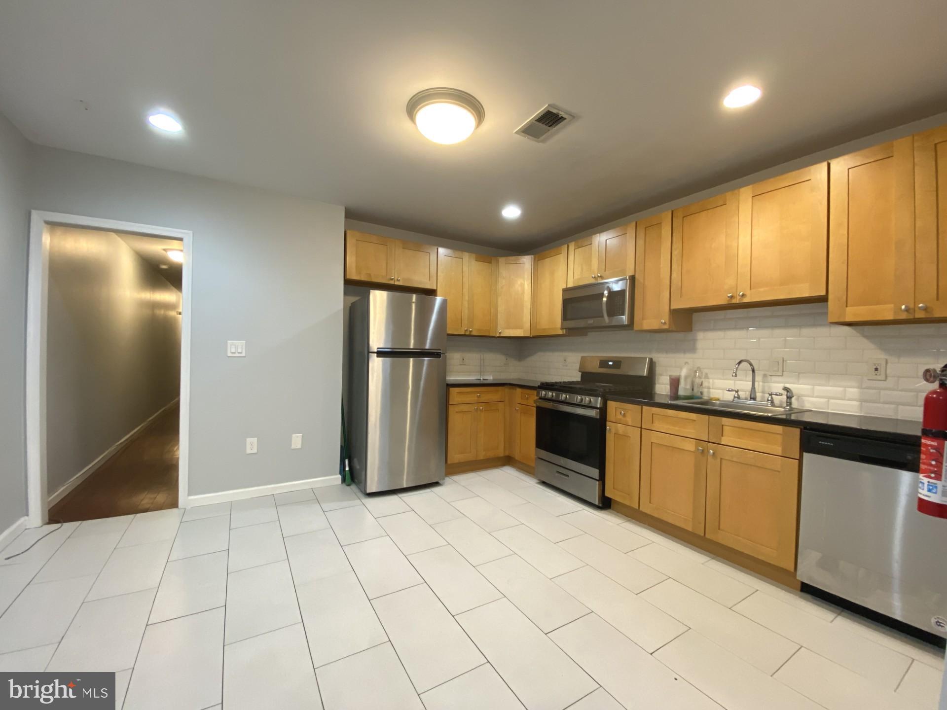 4945 Chestnut Street Philadelphia, PA 19139 - Photo 16 of 27 a kitchen with stainless steel appliances granite countertop a refrigerator and a sink