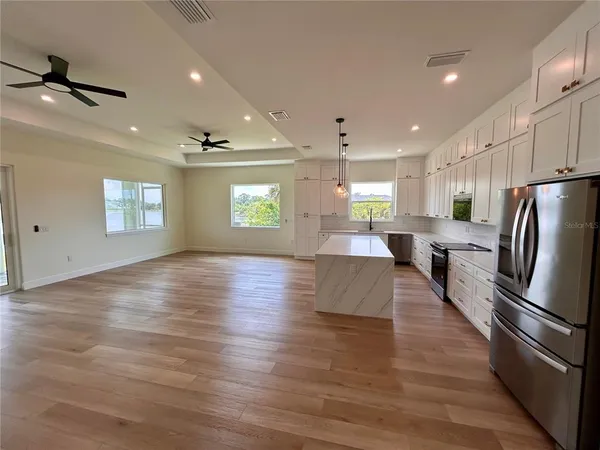 a kitchen with stainless steel appliances granite countertop a refrigerator a stove and a wooden floors