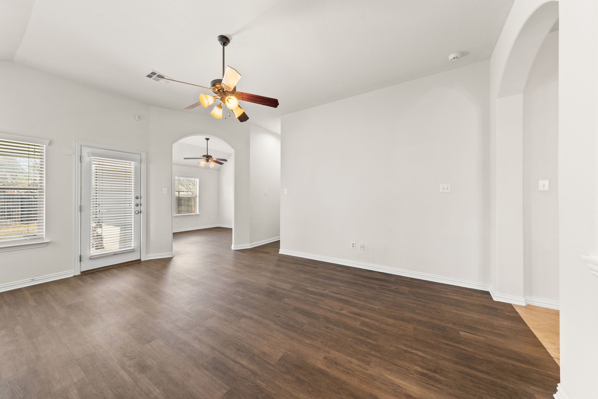 411 Tascate Street Georgetown, TX 78628 - Photo 17 of 41 Rich wood flooring extends through an open layout, featuring elegant arched doorways and natural illumination.