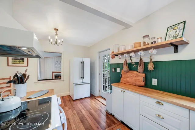 a view of a hallway with wooden floor and a bathroom