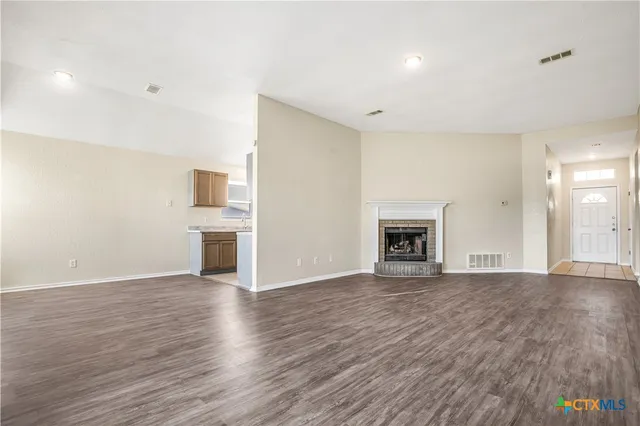 a view of empty room with wooden floor and fireplace