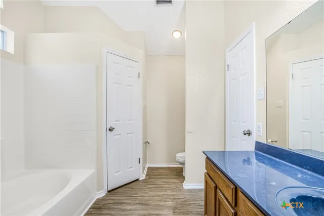 a bathroom with a granite countertop sink a toilet and shower
