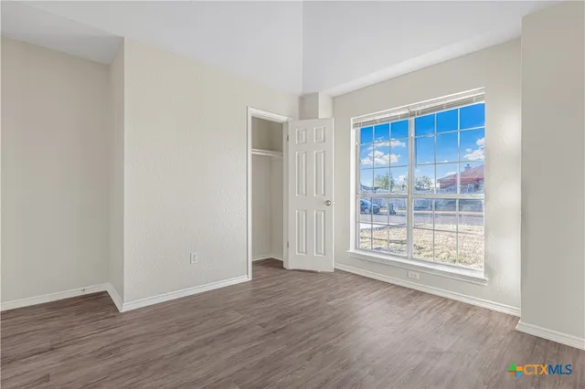 a view of an empty room with wooden floor and a window