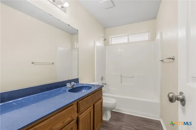 a bathroom with a granite countertop sink a toilet and shower