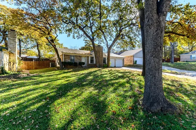 a view of a house with a big yard and large tree