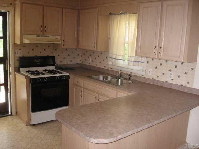 604 Peyton Street Raleigh, NC 27610 - Photo 3 of 6 Kitchen features a gas range, refrigerator,vinyl flooring. Has a eat-in area.