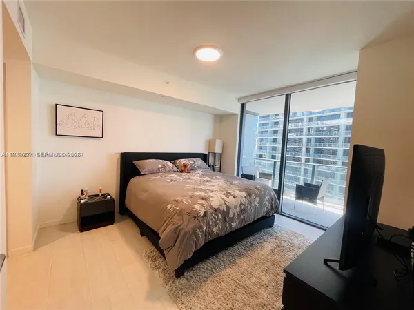 a spacious bedroom with a bed and a flat screen tv