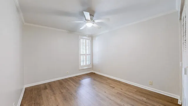 an empty room with wooden floor and a ceiling fan