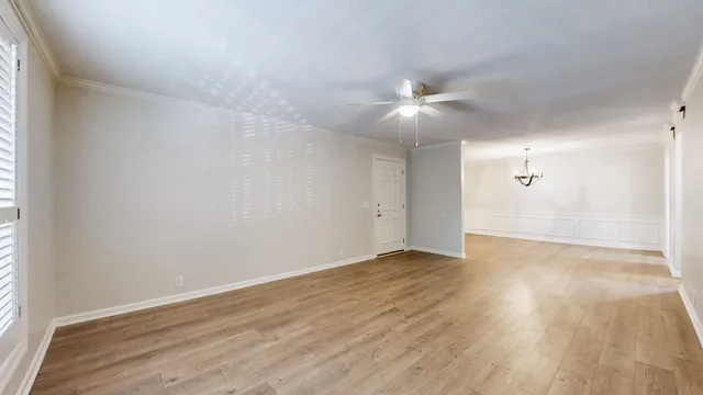 an empty room with wooden floor and fan
