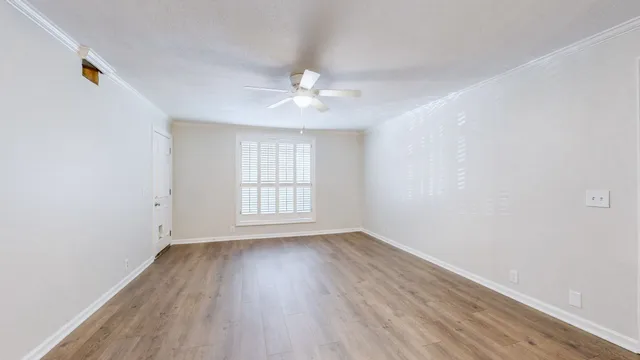 an empty room with wooden floor ceiling fan and windows