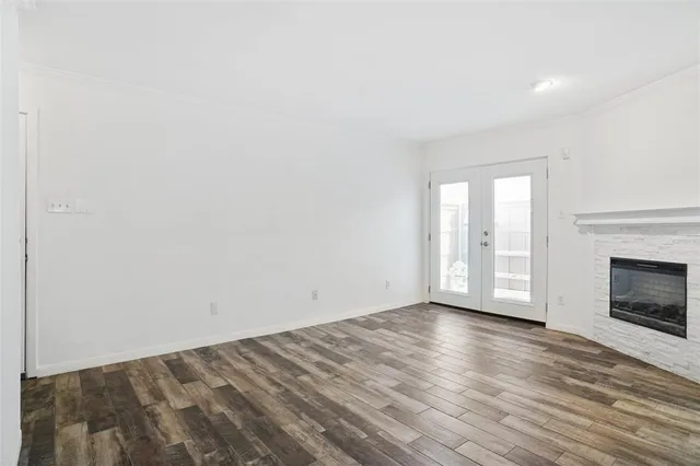 a view of an empty room with wooden floor fireplace and a window