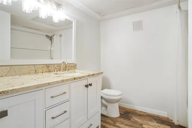 a bathroom with a granite countertop sink a toilet and a mirror