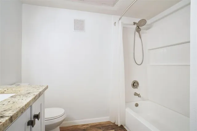 a bathroom with a granite countertop sink a toilet and shower