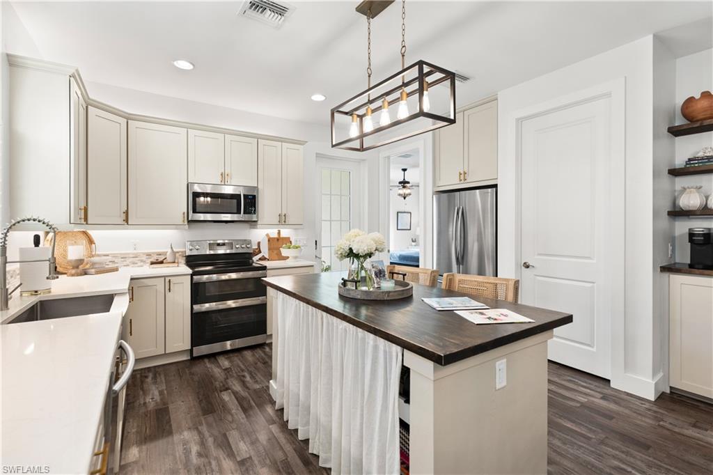 3060 Woodside Avenue Naples, FL 34112 - Photo 12 of 36 a kitchen with stainless steel appliances granite countertop a sink stove and refrigerator